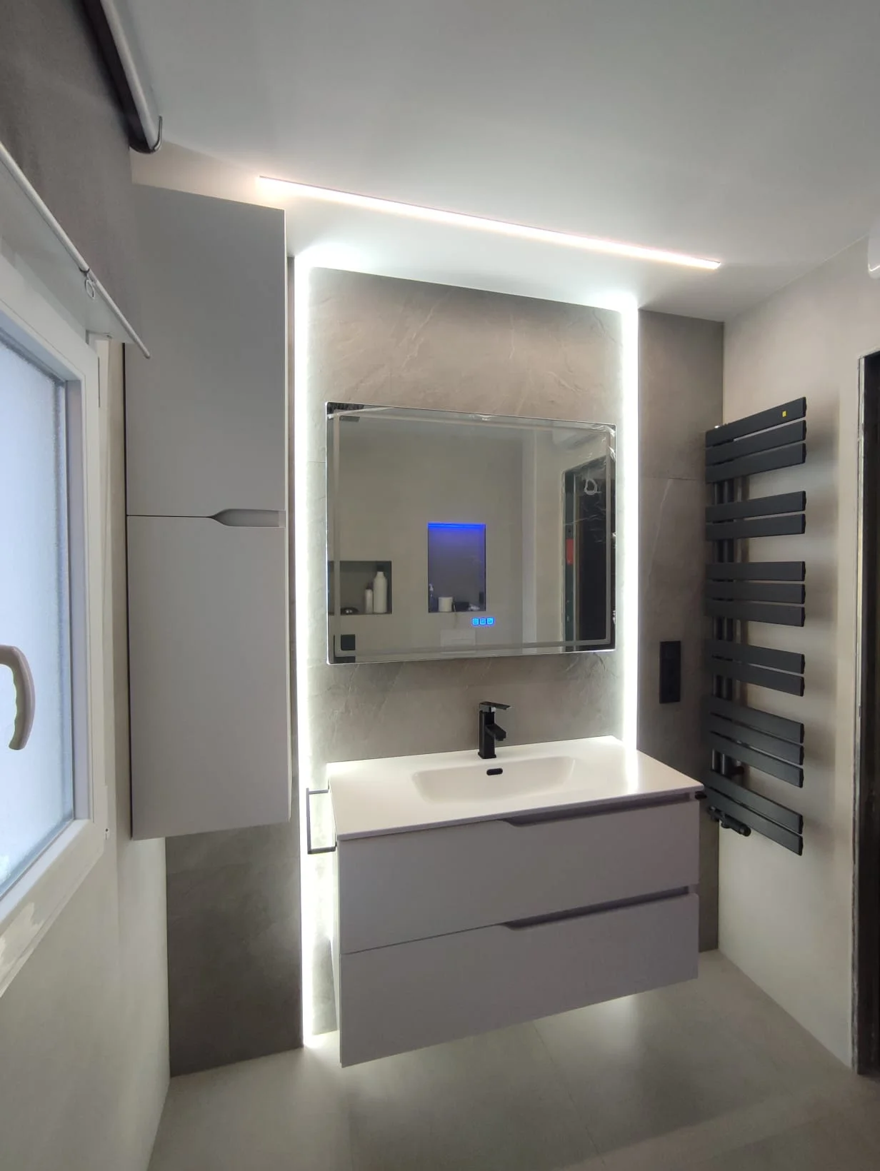 Baño moderno con espejo retroiluminado y toallero en Madrid Sur